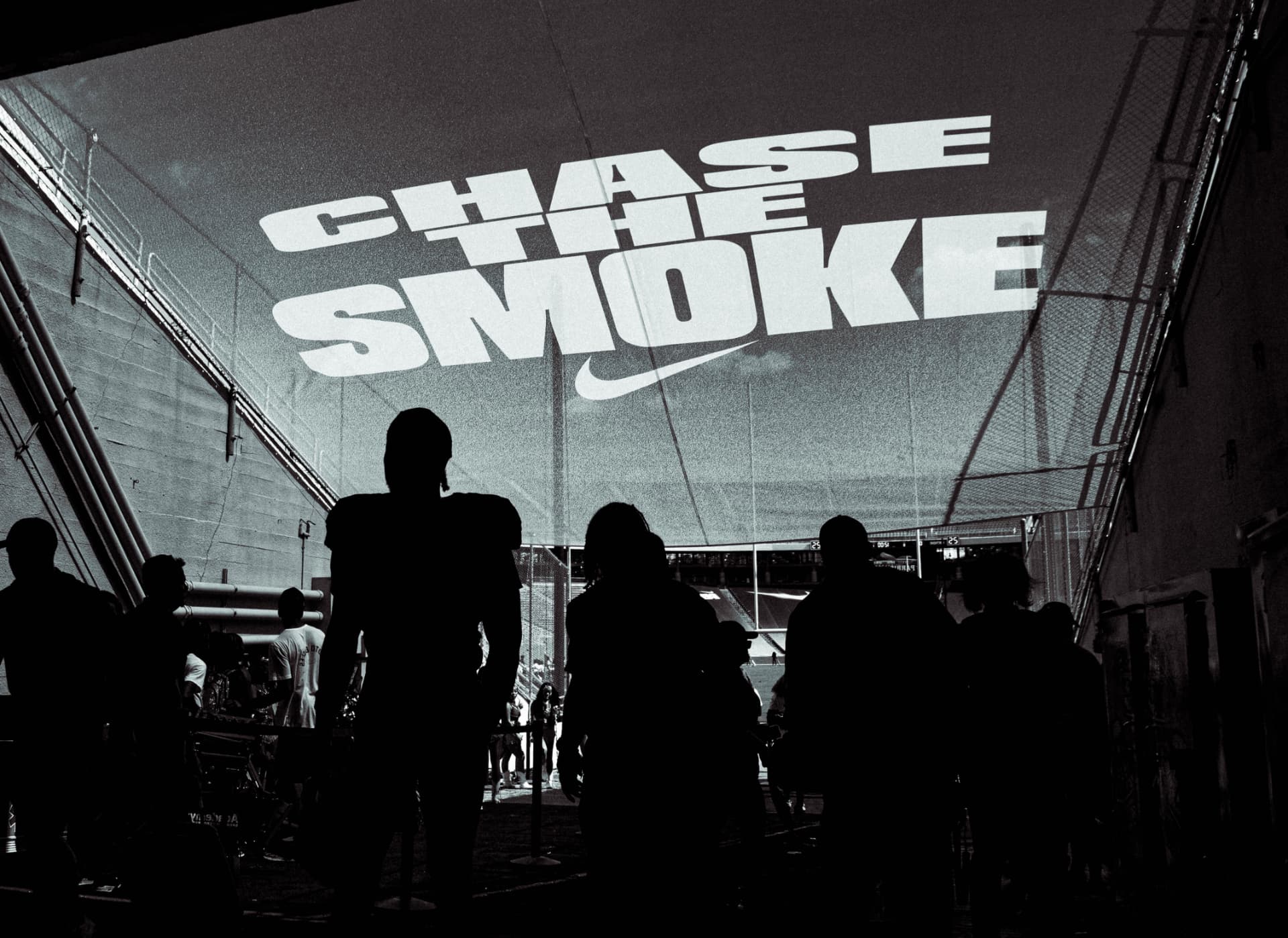Players walking the stadium tunnel beneath a Chase the Smoke banner